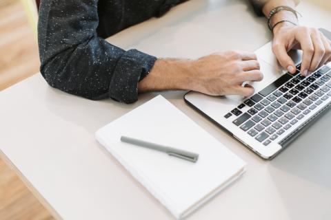 Man sits at desk using laptop